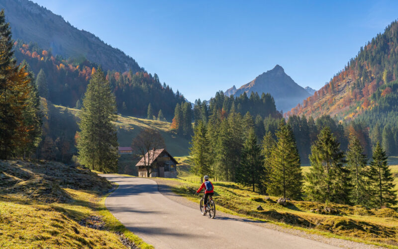 pretty woman riding her electric mountain bike in the mountains of Hinterstein Valley in the upper Allgaeu on warm autumn day, Bavaria, Germany